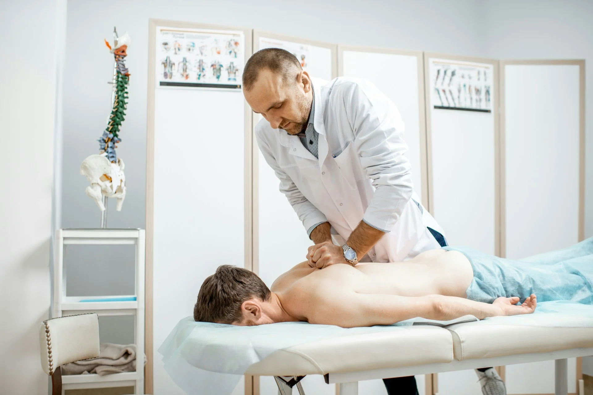 Physician examining a patient’s back and joints during a physical